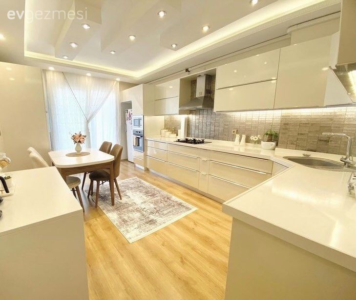 Mutfak, Beyaz, Krem, Modern mutfak, Kulpsuz mutfak dolabı, L-tipi mutfak, Led aydınlatma, Aydınlatma, Spot aydınlatma, Sandalye, Yemek masası, Parke, Mutfak perdesi, Mutfak halısı, Mutfak aksesuarları